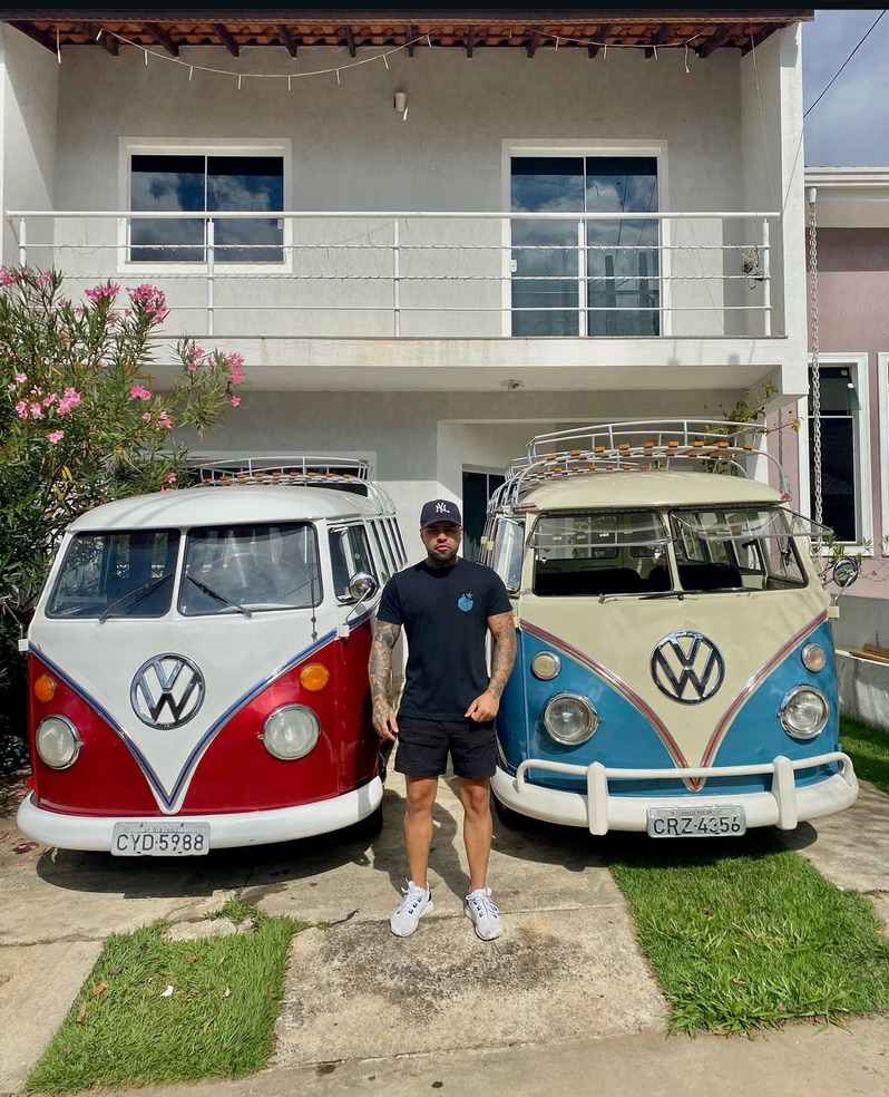 Ewerton standing between two classic Volkswagen T1 buses in Brazil